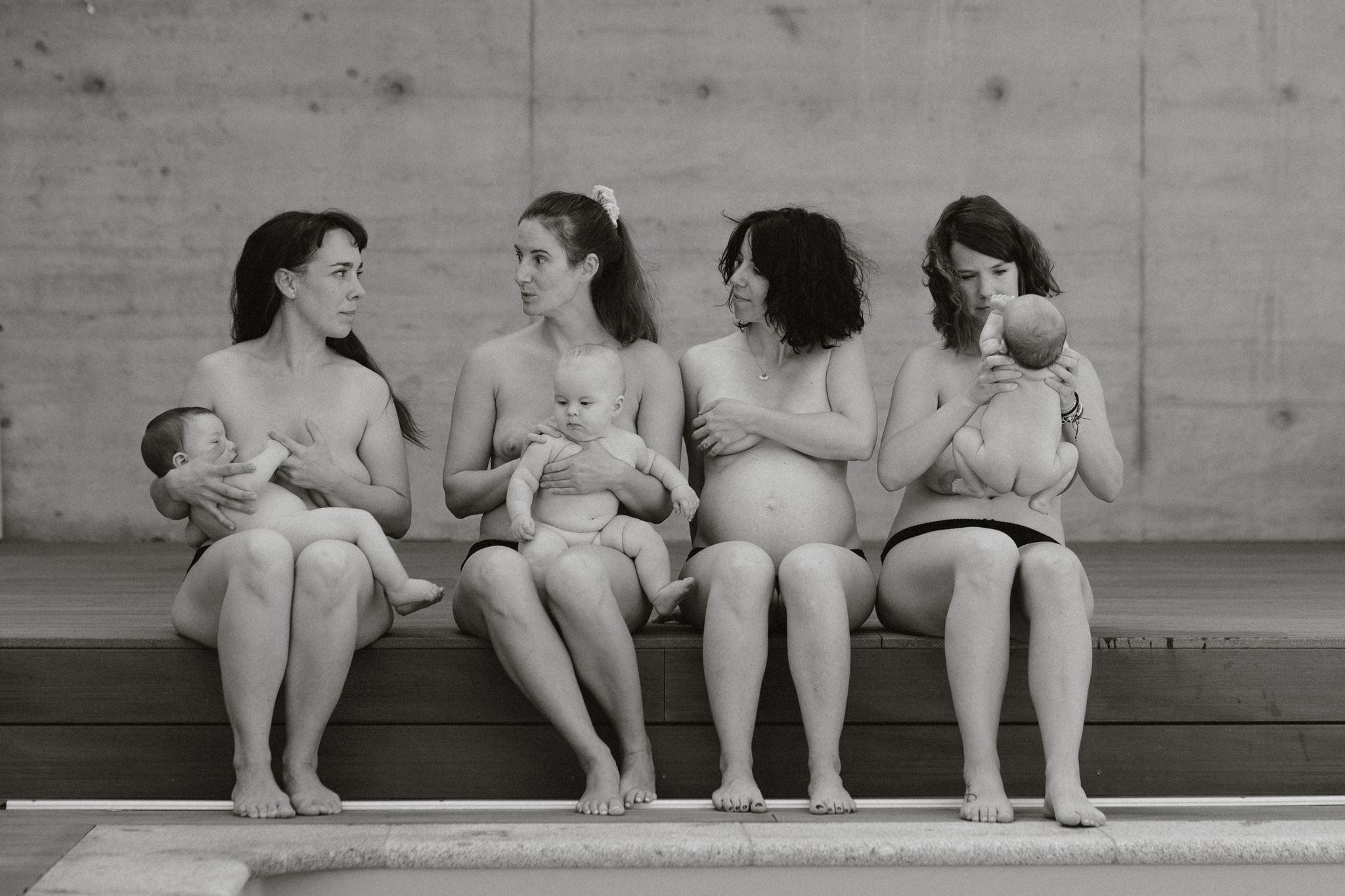 Un groupe de m&egrave;res allaitant leurs enfants au bord de la piscine.