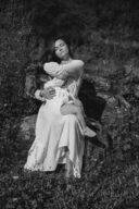 Une mère allaite sa fille assise sur un tronc d'arbre