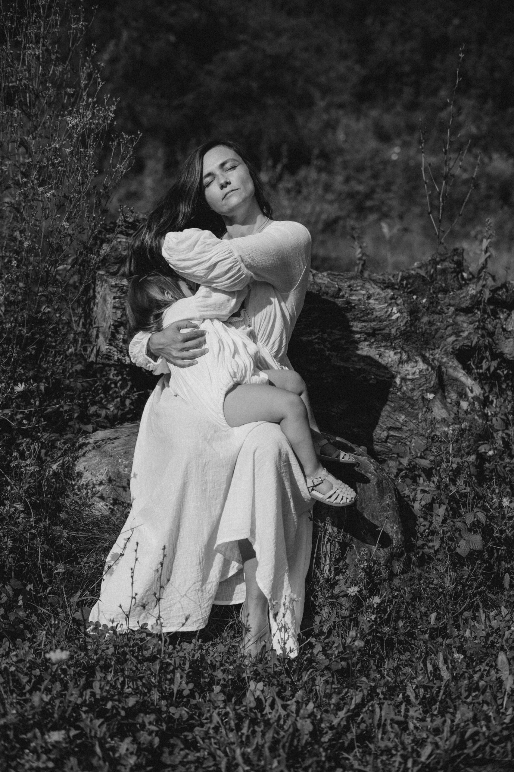 Une m&egrave;re allaite sa fille assise sur un tronc d'arbre