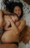 Une mère allaite sa fille avec son chat à côté