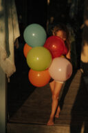 Garçon avec plein de ballons au couché du soleil