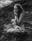 Femme qui allaite en forêt nue en mangeant des baies