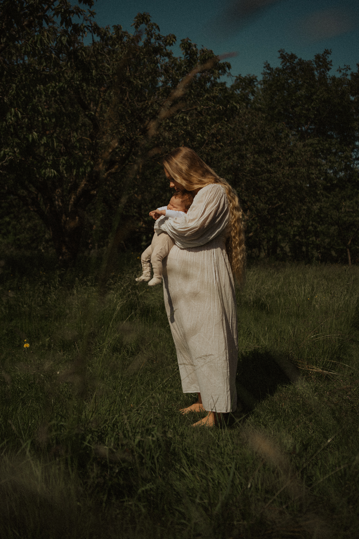 Une m&egrave;re en post-partum porte son b&eacute;b&eacute; dans son jardin
