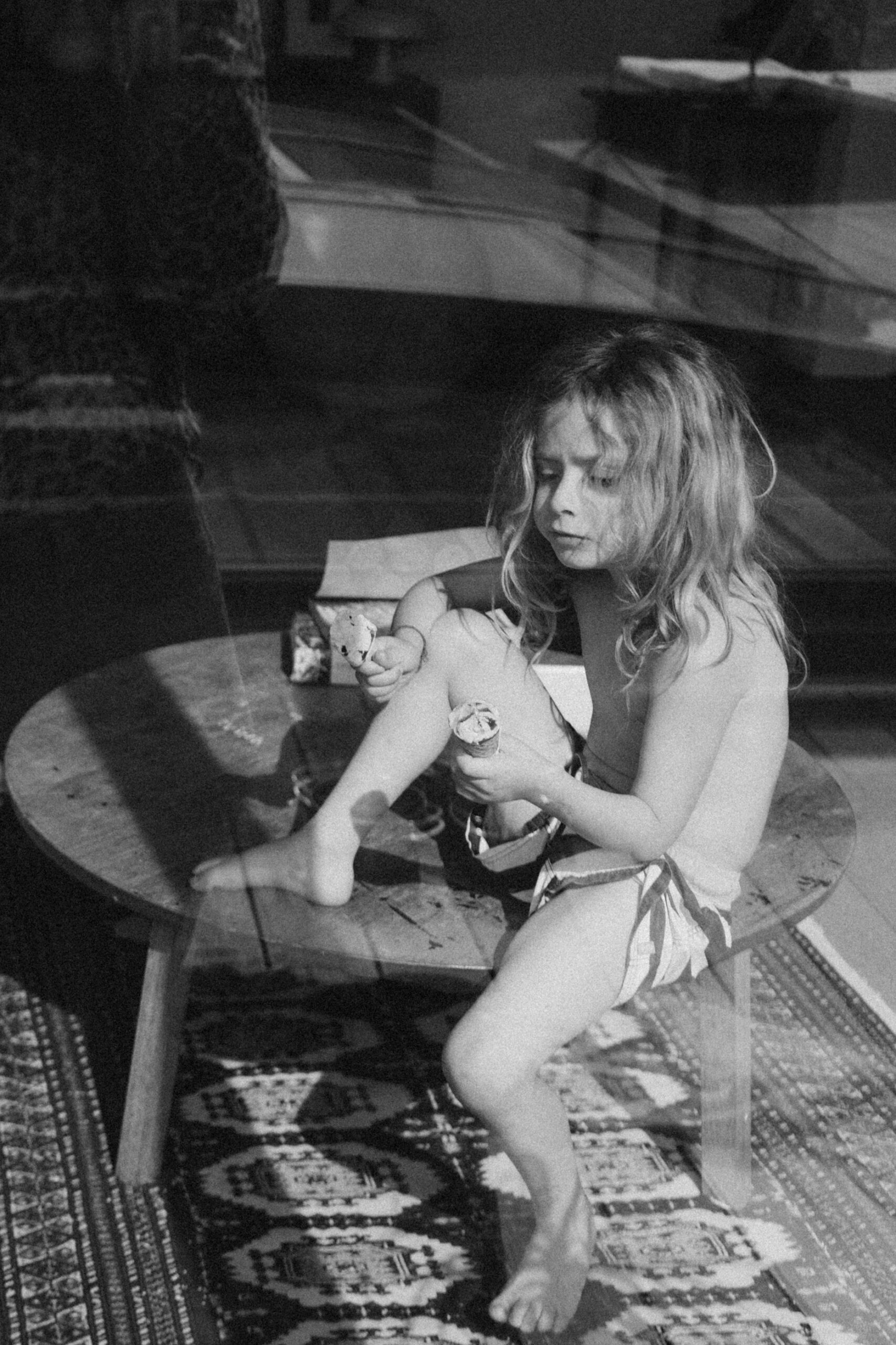 enfant derri&egrave;re la vitre qui mange une glace